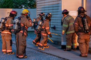 A group of firefighters entering a smoke filled building for a training exercise.
