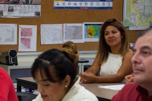 Photo of a woman smiling while paying attention to the instructor in an English as a Second Language course.