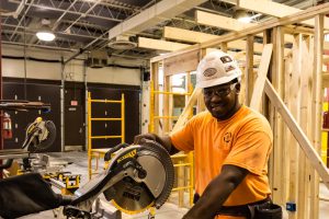 Student using miter saw in construction carpentry.