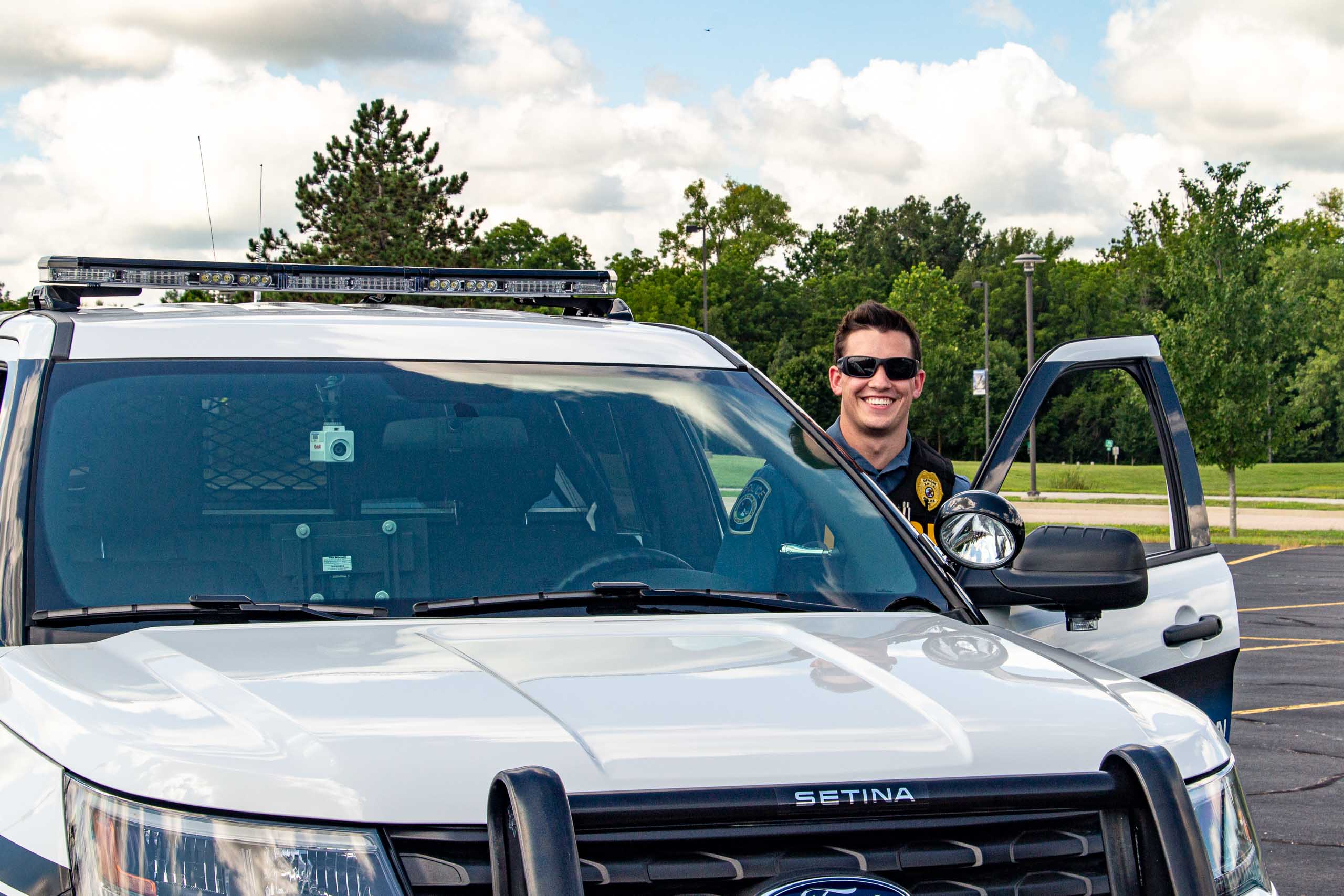 Officer beside patrol car.