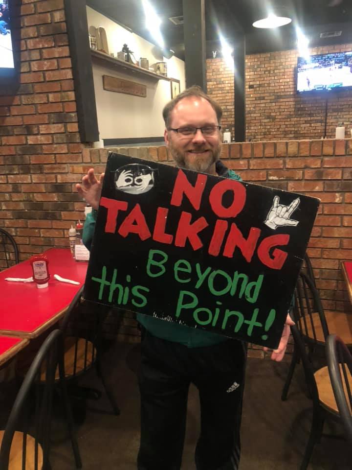 A man holds a sign that says "No talking beyond this point"