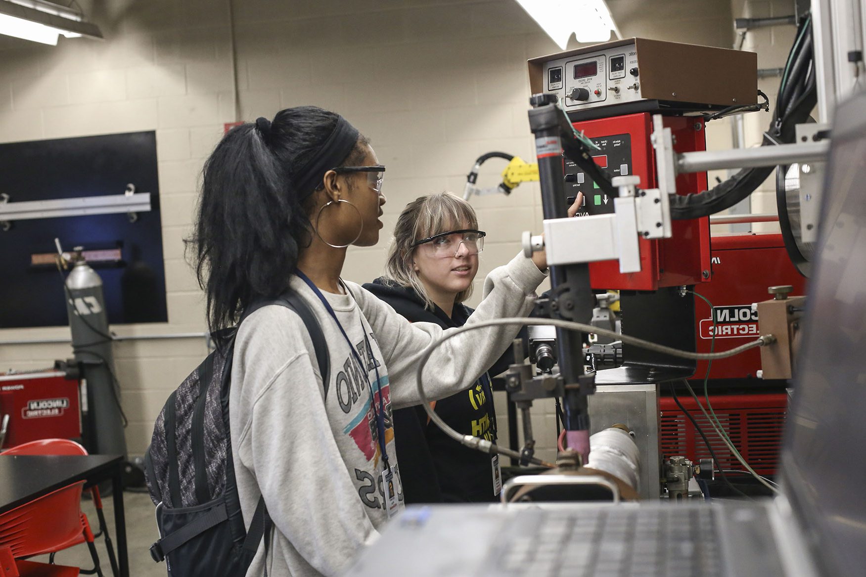 two students view an automated welding machine at the Sam Wolf Granite City Campus