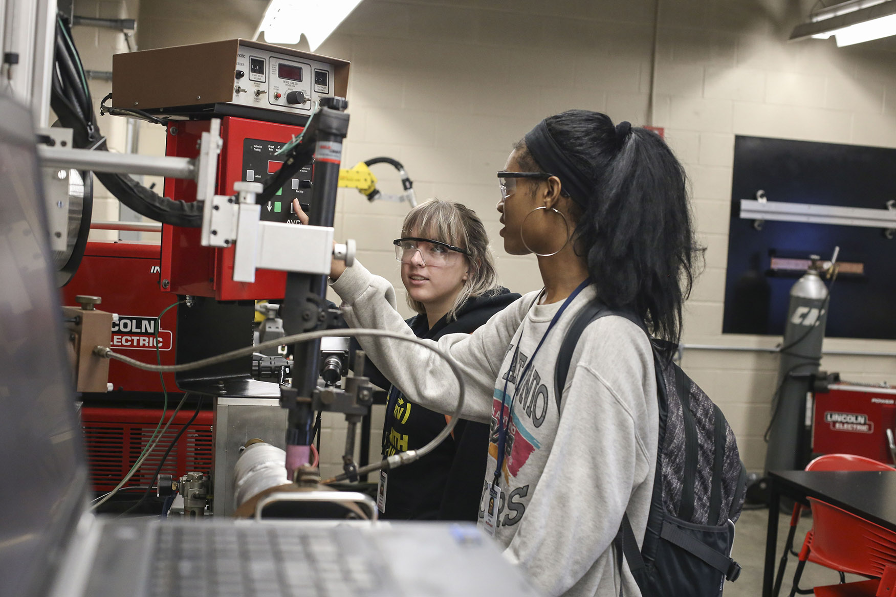 two students view an automated welding machine at the Sam Wolf Granite City Campus