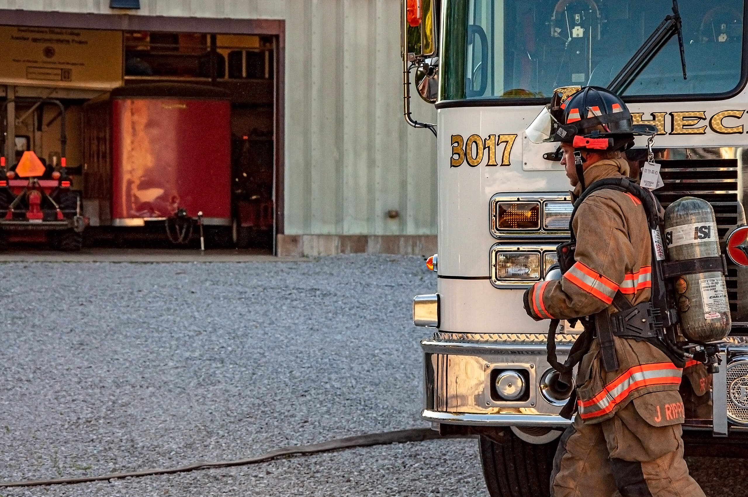 Hecker Fire Science training man in fire gear in front of a fire truck