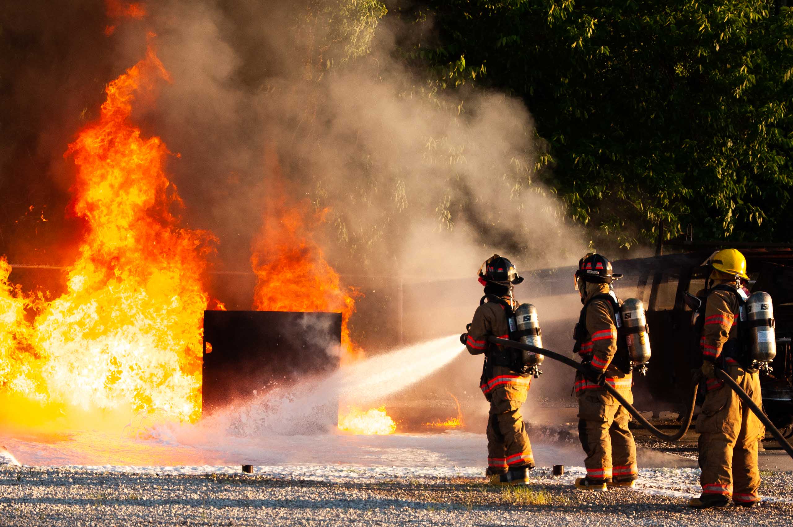 Hecker Fire Science training men in fire gear putting out a fire with a hose